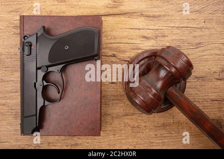 Pistola nera con il codice di diritto e di un martello di corte su sfondo di legno Foto Stock