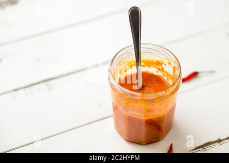 La salsa di Piri Piri è un tipo di salsa di peperoncino piccante usata come condimento o marinata tradizionalmente nella cucina portoghese. Visto qui in un vaso di vetro. Foto Stock