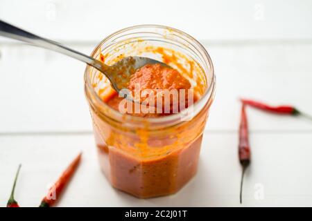 La salsa di Piri Piri è un tipo di salsa di peperoncino piccante usata come condimento o marinata tradizionalmente nella cucina portoghese. Visto qui in un vaso di vetro. Foto Stock