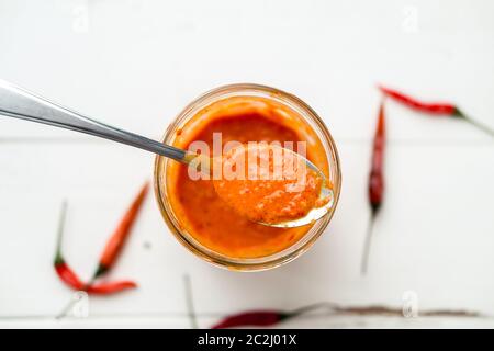 La salsa di Piri Piri è un tipo di salsa di peperoncino piccante usata come condimento o marinata tradizionalmente nella cucina portoghese. Visto qui in un vaso di vetro. Foto Stock