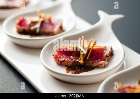 Tataki di tonno è un piatto giapponese che consiste di bistecca di tonno scottata brevemente in fette sottili. Servito come antipasto con salsa di brandy e guarnire al buio Foto Stock