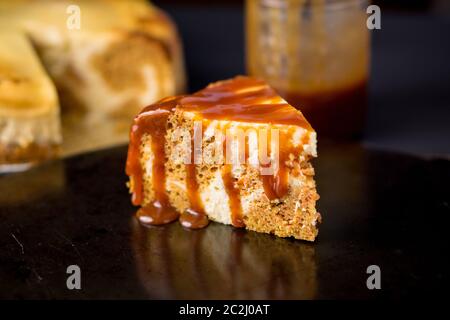Fetta di torta di marmo che è un mix di torta di carote e cheesecake roteati insieme e conditi con salsa al caramello. Un delizioso dolce cremoso. Foto Stock