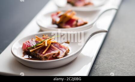 Tataki di tonno è un piatto giapponese che consiste di bistecca di tonno scottata brevemente in fette sottili. Servito come antipasto con salsa di brandy e guarnire al buio Foto Stock