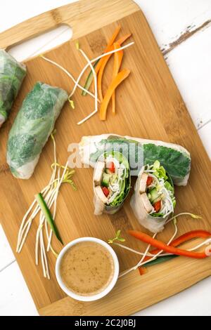 Panini freschi di primavera vietnamiti, ottimi come un antipasto sano con salsa al burro di arachidi per tuffarsi. Il cibo è posto su un tagliere di legno. Foto Stock