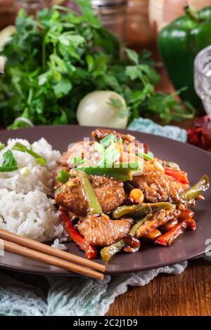 Pollo Kung Pao con peperoni e verdure servite con riso. Piatto tradizionale sichuan Foto Stock