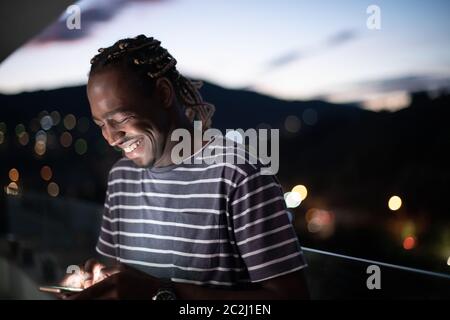 Giovane uomo afro sulla strada di notte utilizzando il telefono Foto Stock