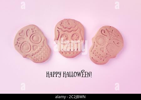 Happy Halloween biglietto di auguri con cranio biscotti allo zenzero, girato dalla parte superiore su un sfondo rosa Foto Stock