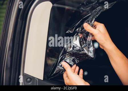 Operaio specializzato peeling al servizio di vecchi film da finestra auto Foto Stock