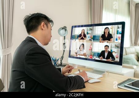 Vista posteriore di un uomo d'affari di razza mista che parla con i suoi colleghi del piano in videoconferenza. Team aziendale multietnico che utilizza il computer per un m online Foto Stock