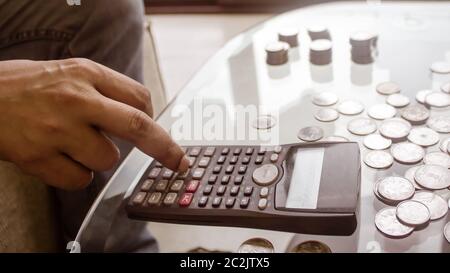 Immagine ritagliata di imprenditore contare monete utilizzando la calcolatrice a scrivania in ufficio. Commercianti lato contare monete. Finanza aziendale e risparmio Inves Foto Stock