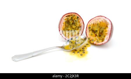 Cucchiaio scooping fuori la polpa e i semi da un viola passione frutta tagliata a metà, su sfondo bianco Foto Stock