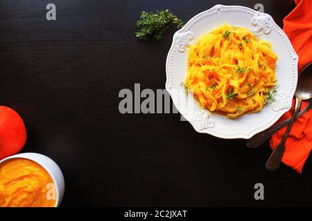 Tagliatelle pastawith Crema di zucca salsa sopra lo sfondo nero. Foto Stock