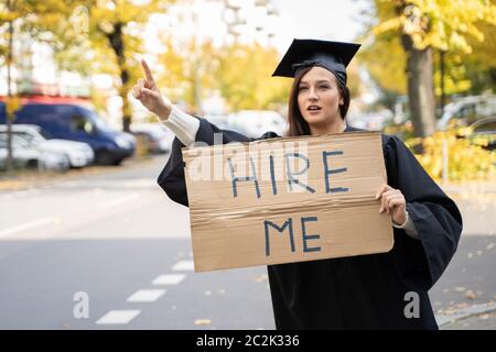 Studente laureato in piedi con noleggio di Me sulla targhetta Street Foto Stock