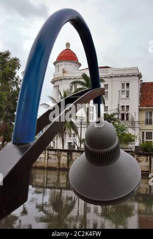 Un edificio con vecchio stile architettonico visto attraverso l'installazione di lampioni sul lato del canale nell'area della Citta' Vecchia di Giacarta. Giacarta, Indonesia. Foto Stock