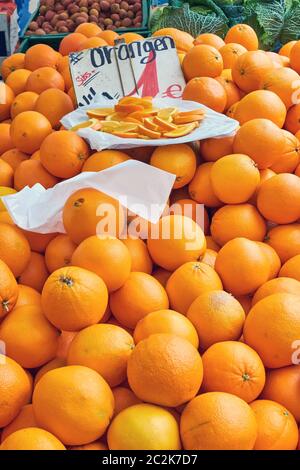 Tangerini per la vendita su un mercato con alcuni pezzi su una piastra Foto Stock