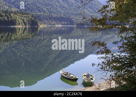 Umore autunnale, barche a remi sulla riva del bacino idrico di Sylvenstein, Baviera, Germania Foto Stock