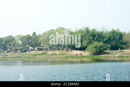 Gange fiume shore (nome locale Damodar ) nel tempo al tramonto con lussureggiante tropicale delle pianure di Gangetic nella Purbasthali, West Bengal, India. Un India rurale landsc Foto Stock