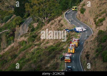 Un elicottero di soccorso è parcheggiato sulla strada, mentre i servizi di emergenza lavorano per liberare il conducente di un veicolo in discesa su una collina a Christchurch, Nuova Zelanda Foto Stock