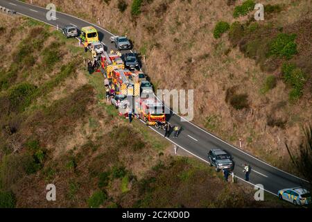 I veicoli per il servizio di emergenza si riuniscono sul lato della strada di un veicolo che è andato fuori strada lungo una collina nella penisola di Banks, Nuova Zelanda Foto Stock