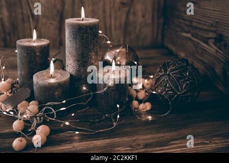 Bella decorazione di natale con quattro candele di advents bruciante su tavola di legno in stile retrò Foto Stock