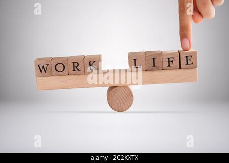 Close-up di una persona del dito di equilibrio tra vita e lavoro dei blocchi su altalena in legno Foto Stock