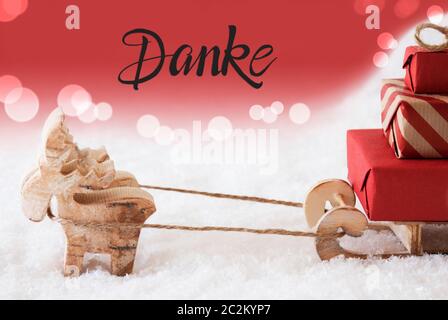 Le renne con slitta e regali di Natale e di neve. Rosso Spumante sfondo con il tedesco Calligraphy Danke significa Grazie Foto Stock