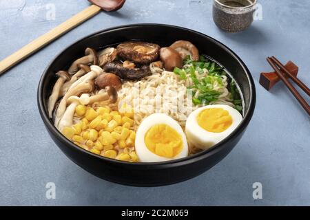 Ramen. Soba Noodles con uova, funghi e verdure, con amore, tradizionale cucchiaio di legno, e bastoncini Foto Stock