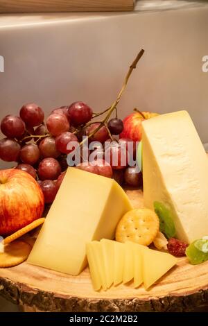 Formaggio gruviera con varietà di frutta e cracker sul piatto di legno in linea a buffet Foto Stock