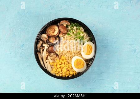 Ramen. Soba Noodles con uova, funghi e ortaggi, overhead shot su uno sfondo blu Foto Stock