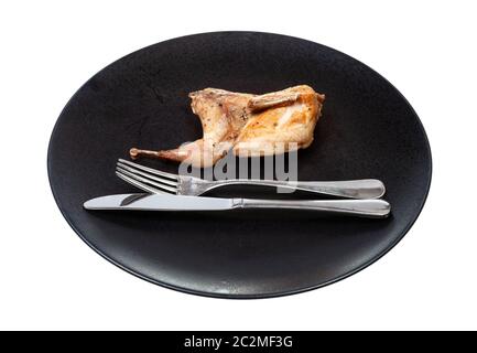 metà della quaglia fritta sulla piastra nera con forchetta e coltello isolato su sfondo bianco Foto Stock