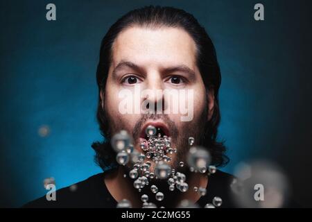 Uomo con bocca aperta che espelle o inala particelle di plastica. Inquinamento ambientale e ingesti di droga Foto Stock