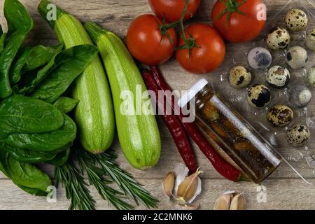 Posando gli ortaggi sulla tavola, la composizione è composta da uova di quaglia, pomodori, zucchine, spinaci e olio d'oliva con spezie, tutti i piedi sul woode Foto Stock