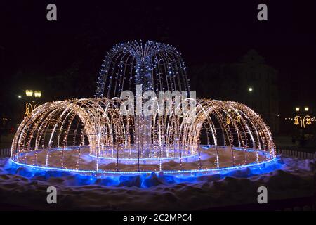 Bella fontana di colorati ghirlande vacanza scintillante e lampeggiante nel parco della città in inverno Foto Stock