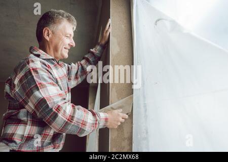 Diligente stuccatore lavorando su una finestra Foto Stock