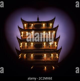 Fotografato al tramonto tradizionale stile cinese torre pagoda in legno visto attraverso la cornice in una forma a cuore, Wulingyuan ingresso alla Zhangjiajie na Foto Stock