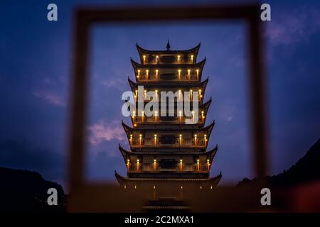 Fotografata al tramonto, la pagoda in legno in stile tradizionale cinese visto attraverso la cornice, l'ingresso di Wulingyuan al parco nazionale Zhangjiajie, Huna Foto Stock