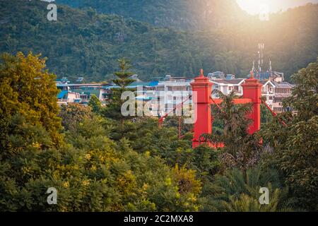 Ponte rosso su via Sanduo Lu nella città di Guilin con montagne carsiche sullo sfondo, provincia Guangxi, Cina Foto Stock