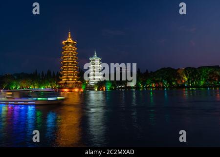 Barche turistiche che navigano di fronte alle Torri delle Pagodas di Luna e del sole illuminate di notte a Shanhu o al Lago Shan nella città di Guilin, provincia di Guangxi, Cina Foto Stock