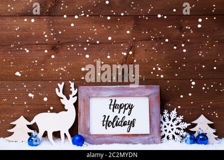 Telaio con la calligrafia Inglese Buone Vacanze. Blue decorazione di Natale come la sfera, albero e cervi. Sfondo di legno con la neve Foto Stock