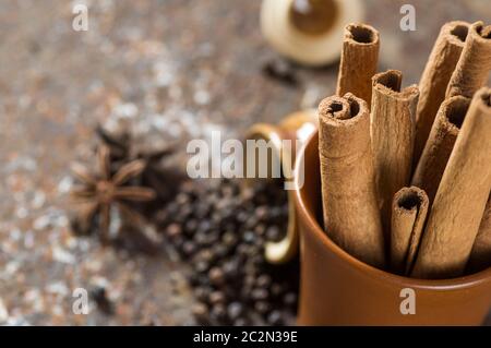 Le spezie e le erbe. Il cibo e la cucina ingredienti. Bastoncini di cannella, anice stelle, pepe nero su sfondo a trama Foto Stock