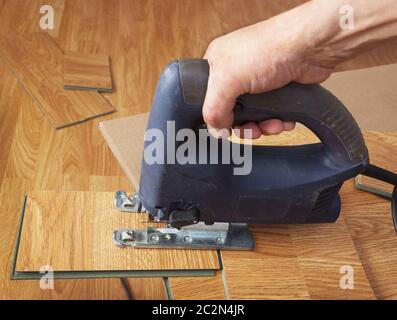 Mano con seghetto alternativo elettrico per tagliare il foglio di legno  Foto stock - Alamy