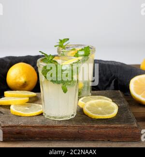 Estate bevanda rinfrescante limonata con limoni, foglie di menta in un bicchiere, accanto agli ingredienti per la realizzazione di un cocktail Foto Stock