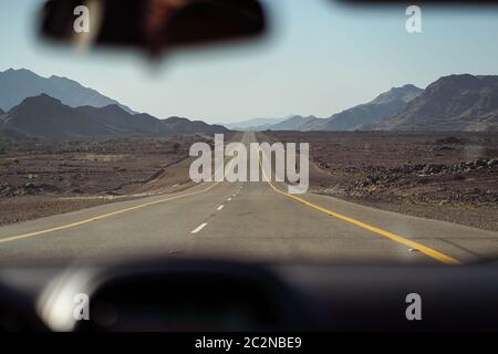 Bellissima autostrada dritta circondata da montagne rocciose vista dall'interno dell'auto, in Arabia Saudita Foto Stock