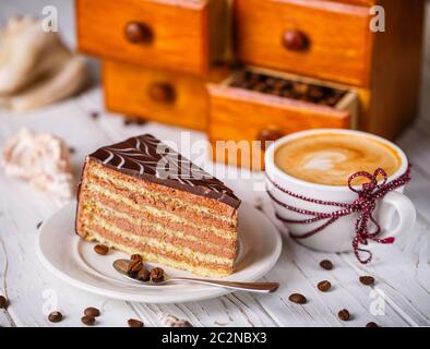 Torta al cioccolato con una tazza di cappuccino caldo sul tavolo con guscio. Foto Stock