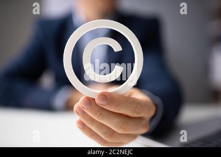 Persona che detiene il copyright bianco segno in mano Foto Stock