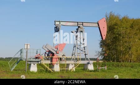 Pozzo di petrolio e gas in campo petrolifero, profilato contro il cielo blu Foto Stock