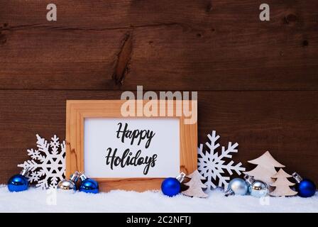 La calligrafia Inglese Buone Vacanze. Blue ornamento di Natale come albero, il simbolo del fiocco di neve e la sfera. Sfondo di legno con la neve Foto Stock