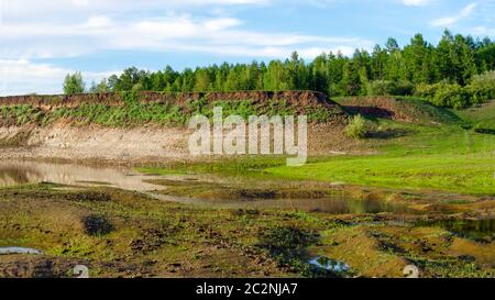 Piccoli canali e acqua del fiume su una ripida collina con una foresta nell'estremo nord nella taiga di Yakutia. Foto Stock