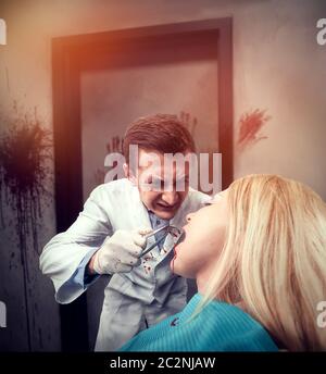 Dentista di paura MAD che estrae un dente in donna in camera sporca Foto Stock