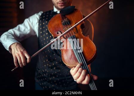 Il violinista maschio riproduzione di musica classica al violino. Fiddler uomo con uno strumento musicale Foto Stock